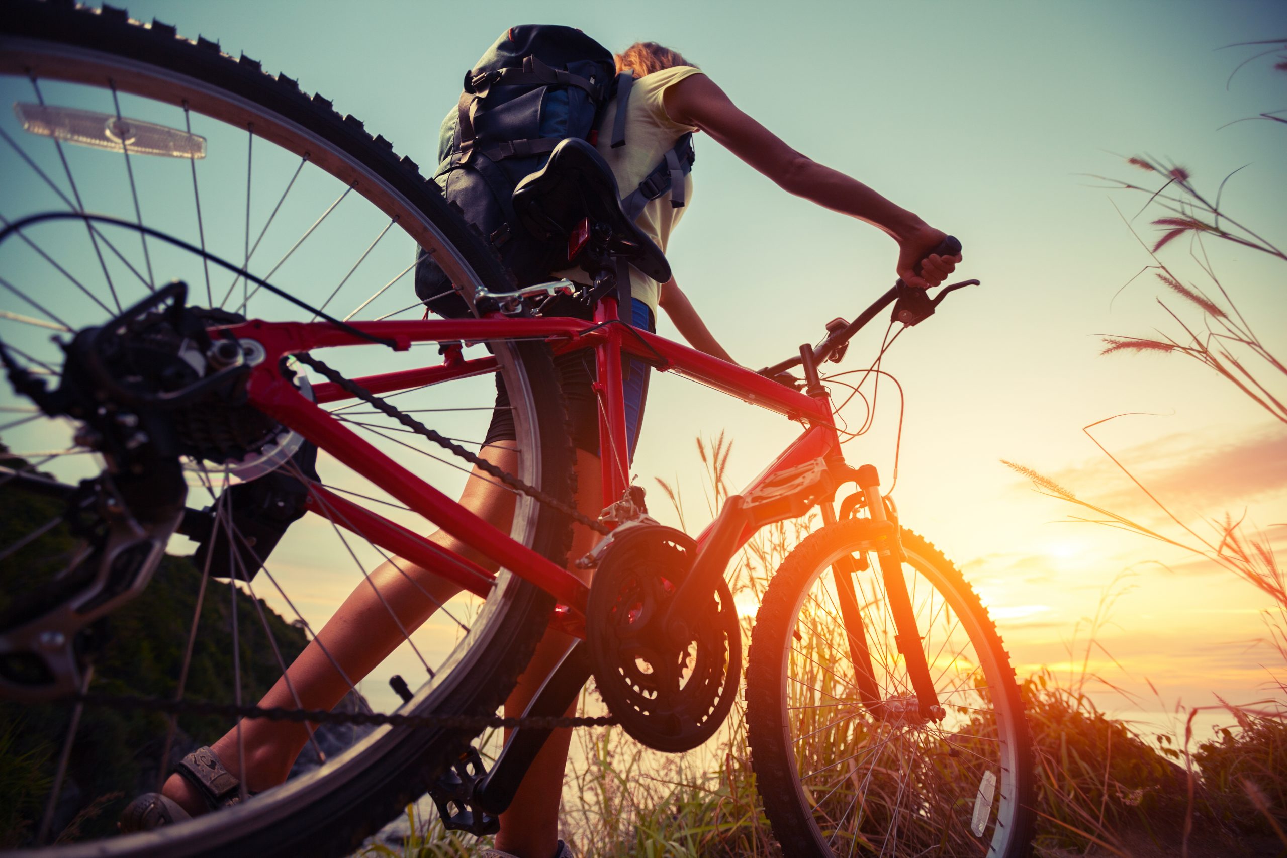 Cyclist wheels bike towards a sunset