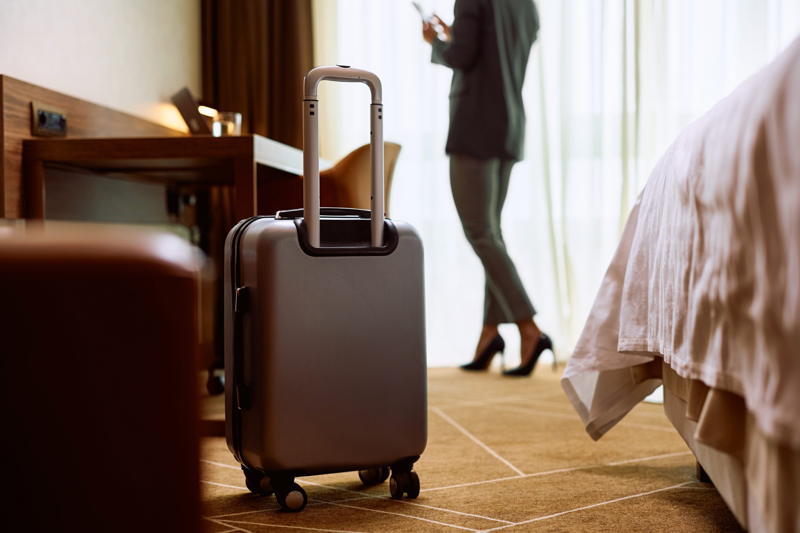 A guest in a hotel room with their suitcase